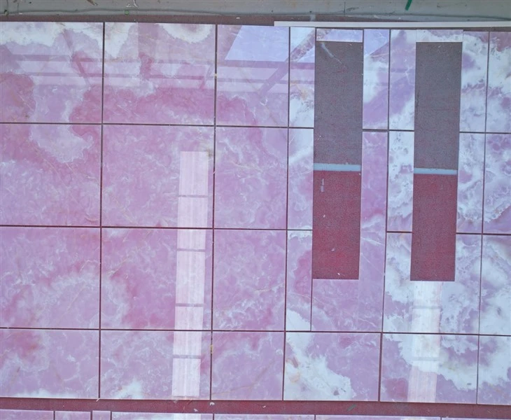 Complete factory dry layout of polished Pink Onyx wall tiles for checking piece positions, vein continuity, color variation, cutouts and overall visual coordination.